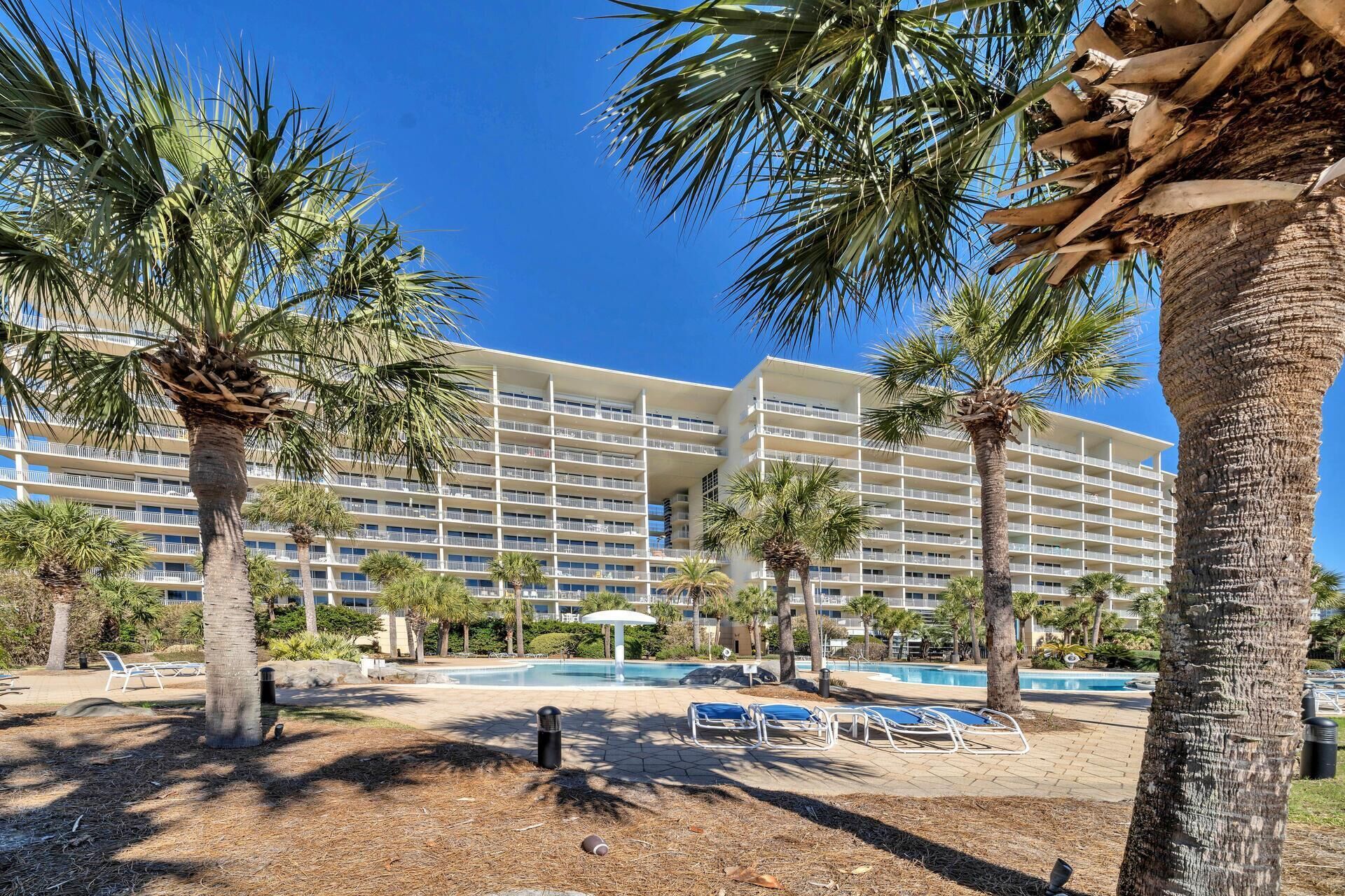 Ein Hotel mit mehreren Balkonen, einem Swimmingpool und Palmen.