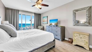 Quarto com cama grande, penteadeira, espelho e ventilador de teto.
