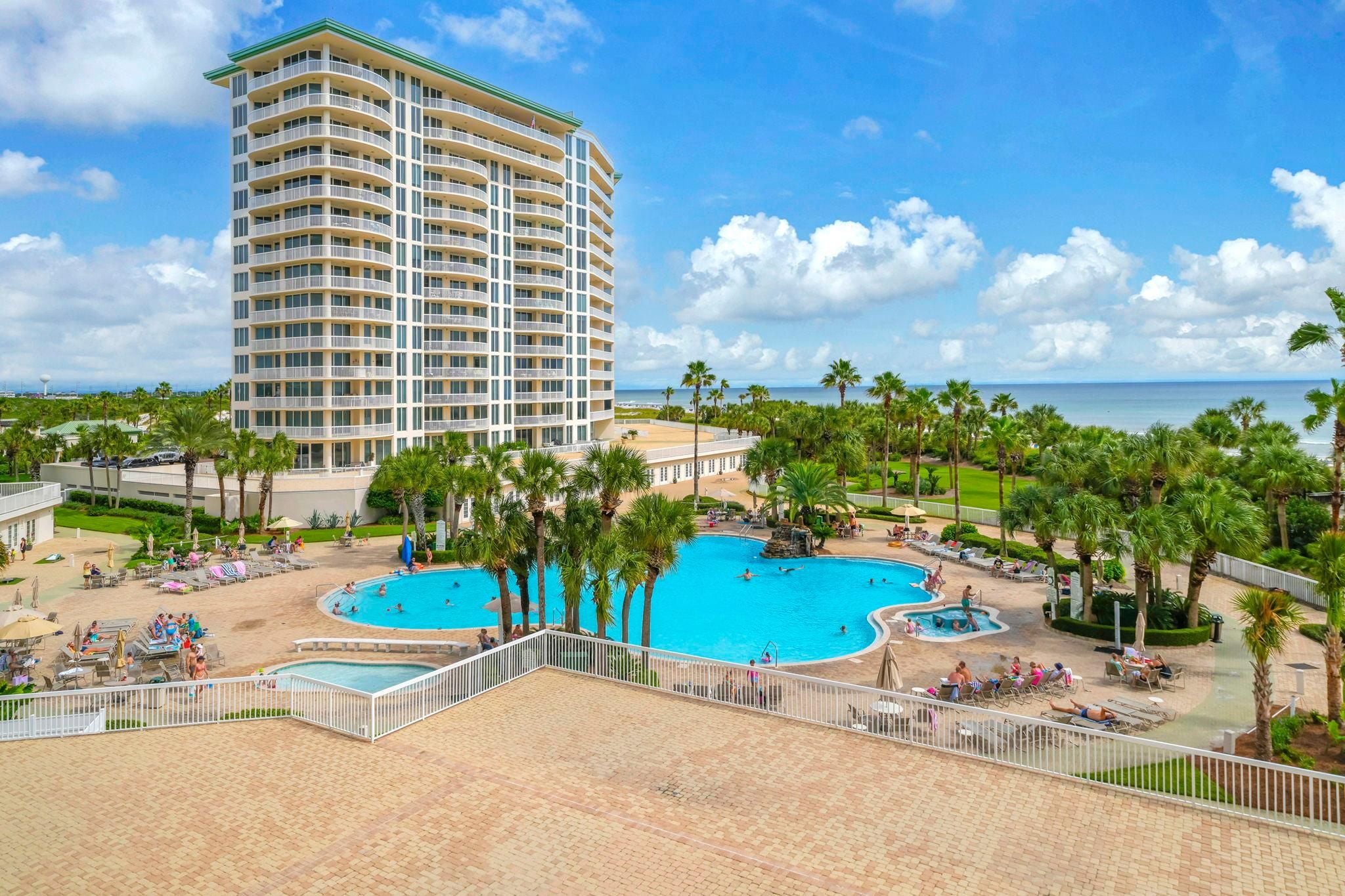 A hotel with a large pool area, multiple swimming pools, and a view of the ocean.