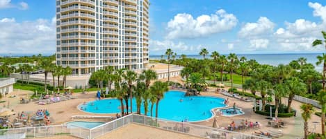 A hotel with a large pool area, multiple swimming pools, and a view of the ocean.