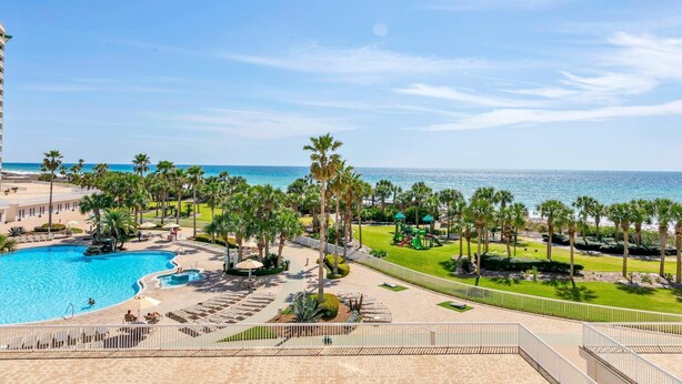 Un resort con piscina, palmeras y vista al océano.