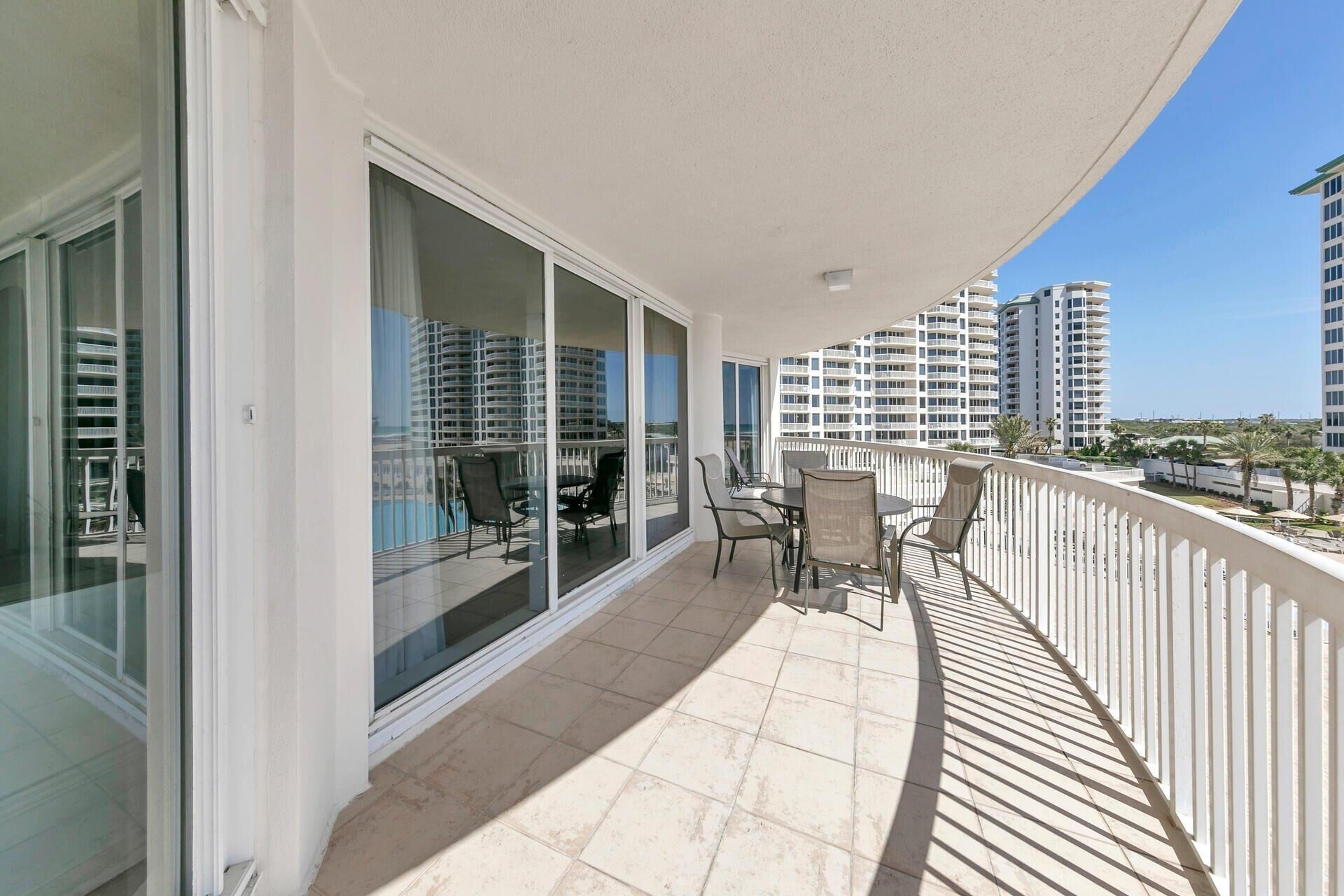 A balcony with a view of high-rise buildings, a tiled floor, and outdoor furniture.