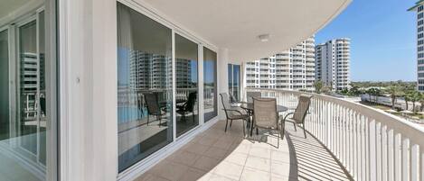 A balcony with a view of high-rise buildings, a tiled floor, and outdoor furniture.
