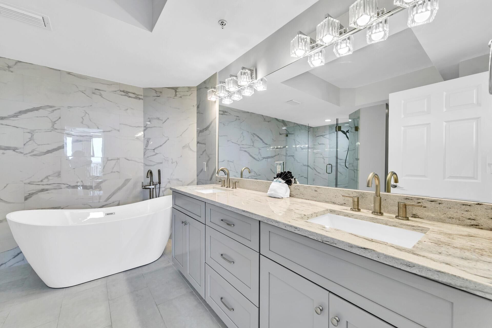 Un baño moderno con una bañera independiente, un lavamanos grande con doble lavabo y un espejo amplio.