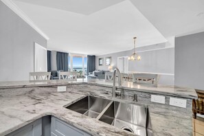 A modern kitchen with a large island, stainless steel sink, and a view to the outside. - St. Maarten 402 at Silver Shells (Destin)