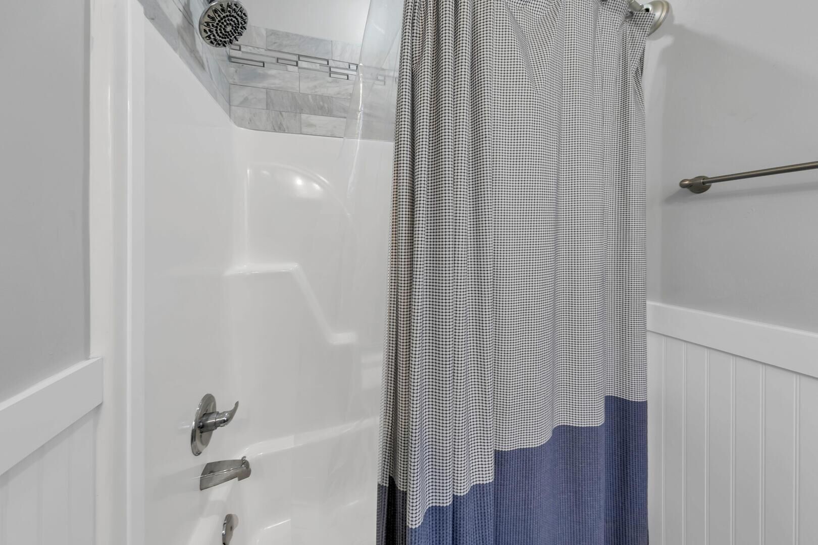 Une salle de bain avec une baignoire blanche, une douche dotée d’une porte en verre et un porte-serviettes.