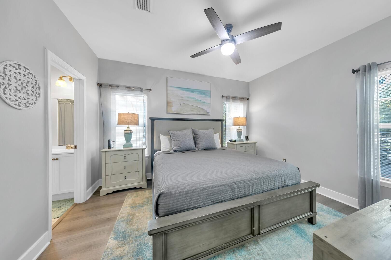 Une chambre à coucher avec un lit, des tables de chevet, un ventilateur de plafond et une fenêtre avec des rideaux.