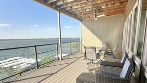 A wooden deck with a view of the water, a table, chairs, and a ceiling fan. - Bayside Vacation Condo Rental 4 bedrooms!! (Arnolds Park)