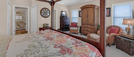A bedroom with a four-poster bed, a dresser, a chair, and a cabinet.