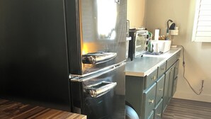 A compact kitchen with a black refrigerator, wooden countertop, and grey herringbone flooring. - Hidden gem. Tiny home in mural district.  (Blythe)