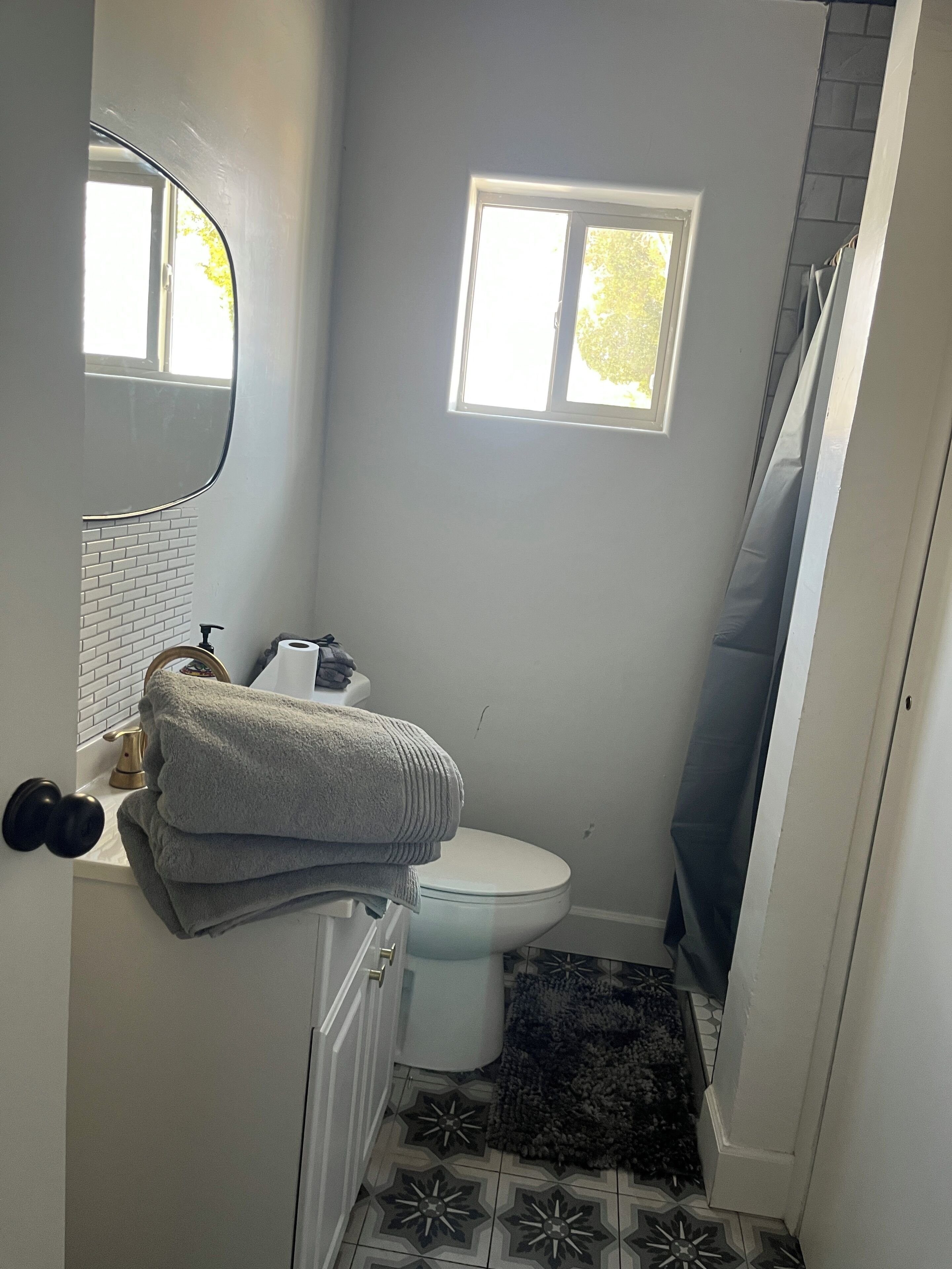 Ein kleines Badezimmer mit Toilette, Waschbecken, Spiegel und einem kleinen Fenster.