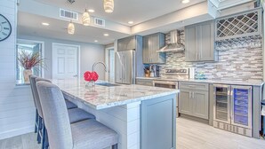 A modern kitchen with a marble island, stainless steel appliances, and a wine rack. - St. Maarten 701 at Silver Shells (Destin)