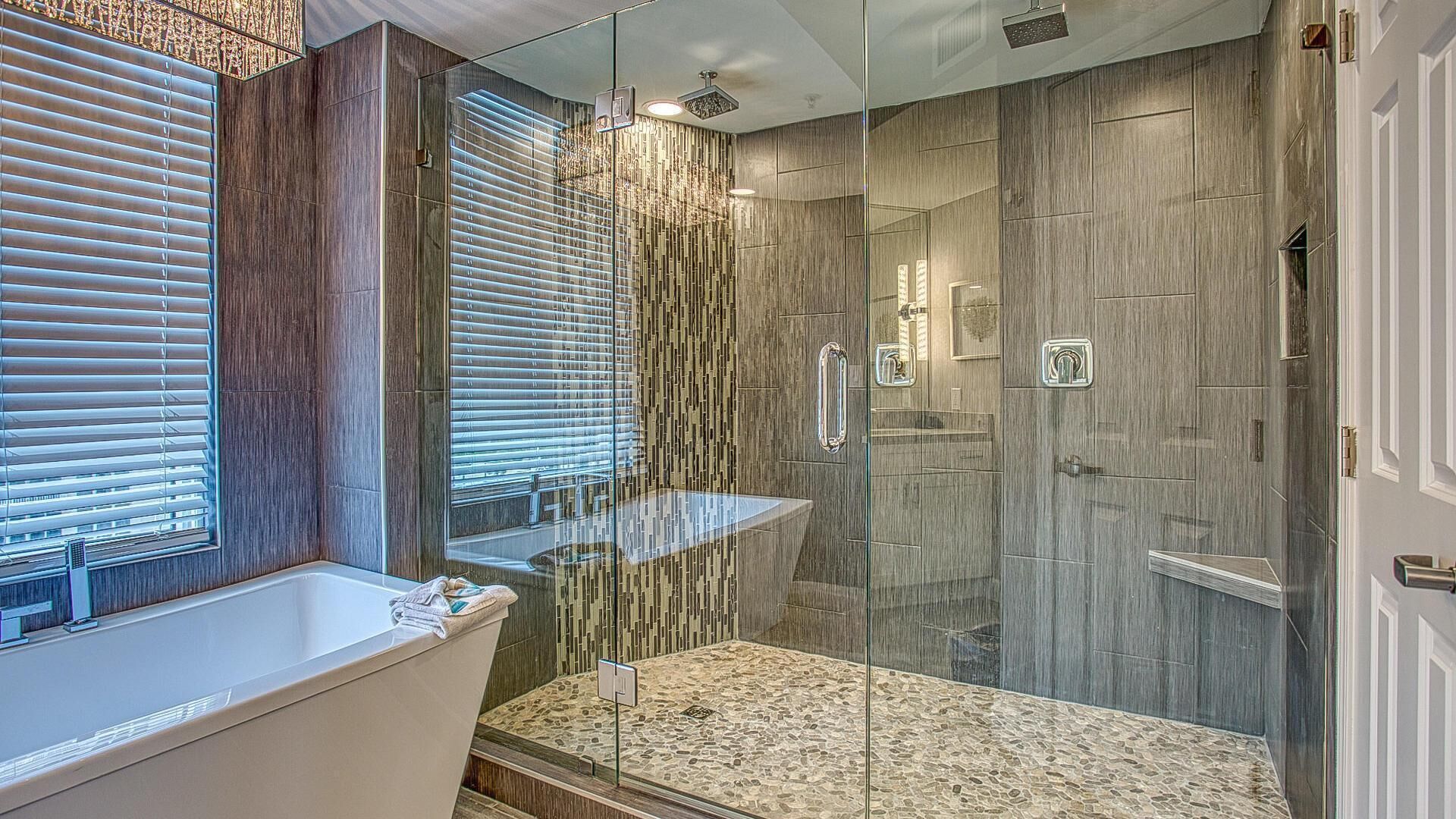 A modern bathroom with a glass-enclosed shower, a freestanding bathtub, and a vanity with a mirror.