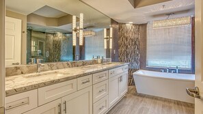 A modern bathroom with a large mirror, marble countertop, and a bathtub. - St. Maarten 701 at Silver Shells (Destin)