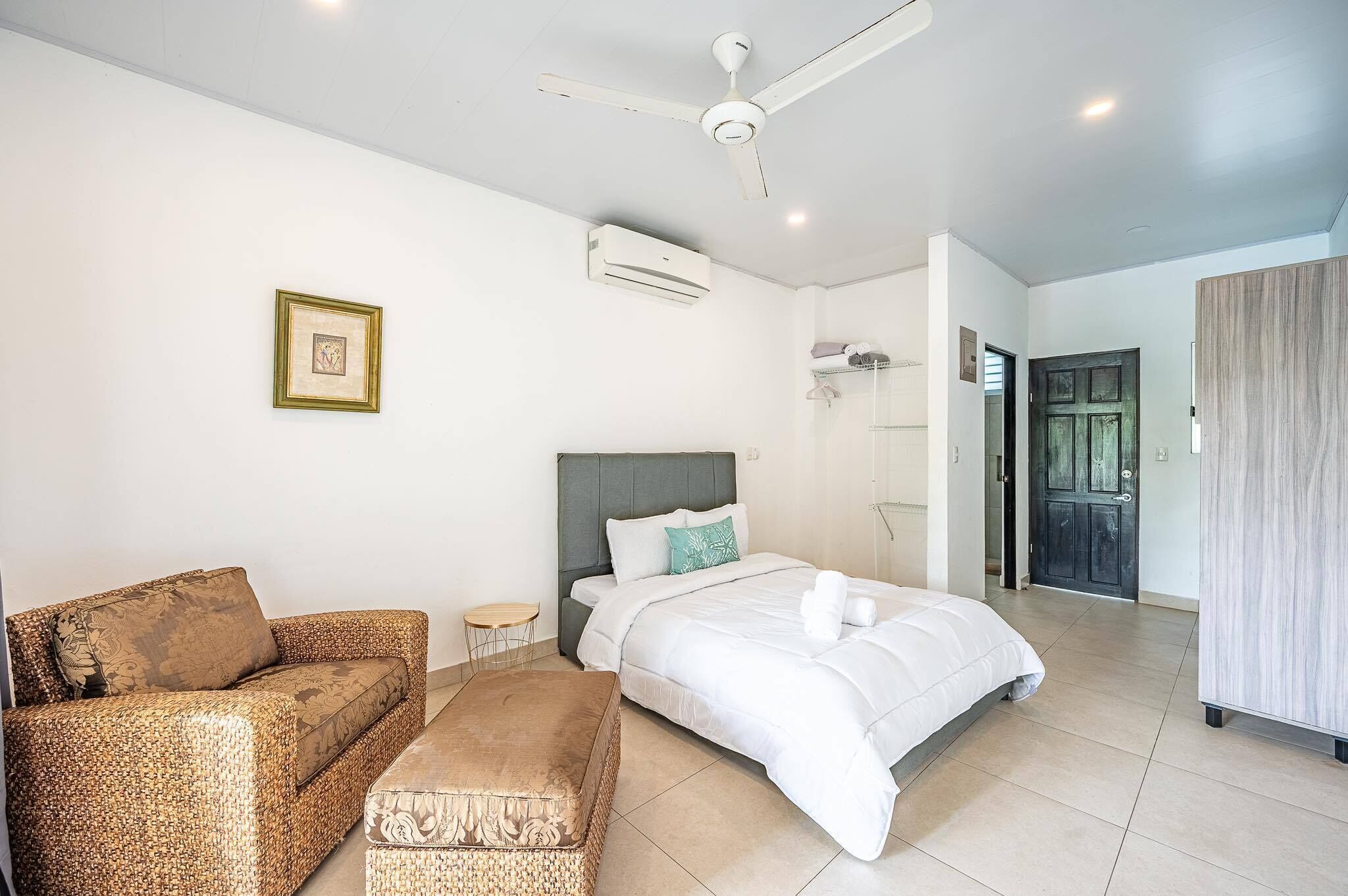 Um quarto moderno com cama, sofá, uma mesinha e um ventilador de teto.