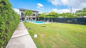 A modern house with a swimming pool, a concrete pathway, and a well-maintained lawn. - Gorgeous Studios in the heart of Jaco. (Jacó)