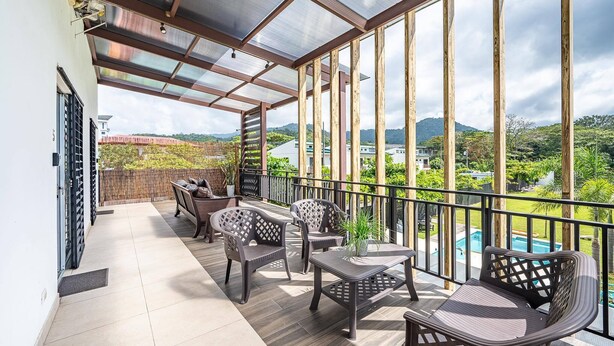 A covered balcony with a view of a swimming pool and mountains. - Gorgeous Studios in the heart of Jaco. (Jacó)