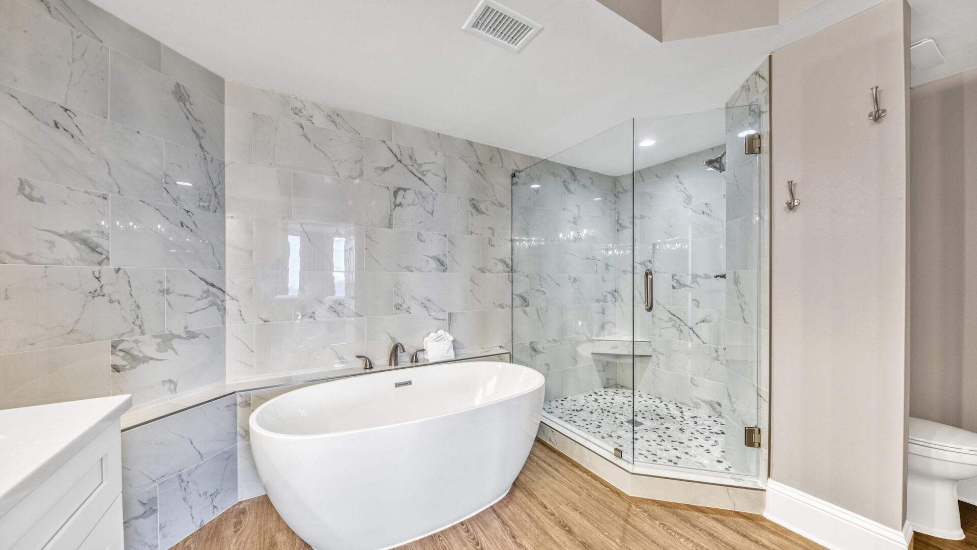 Ein modernes Badezimmer mit freistehender Badewanne, einer in Glas eingefassten Dusche und Marmorwänden.