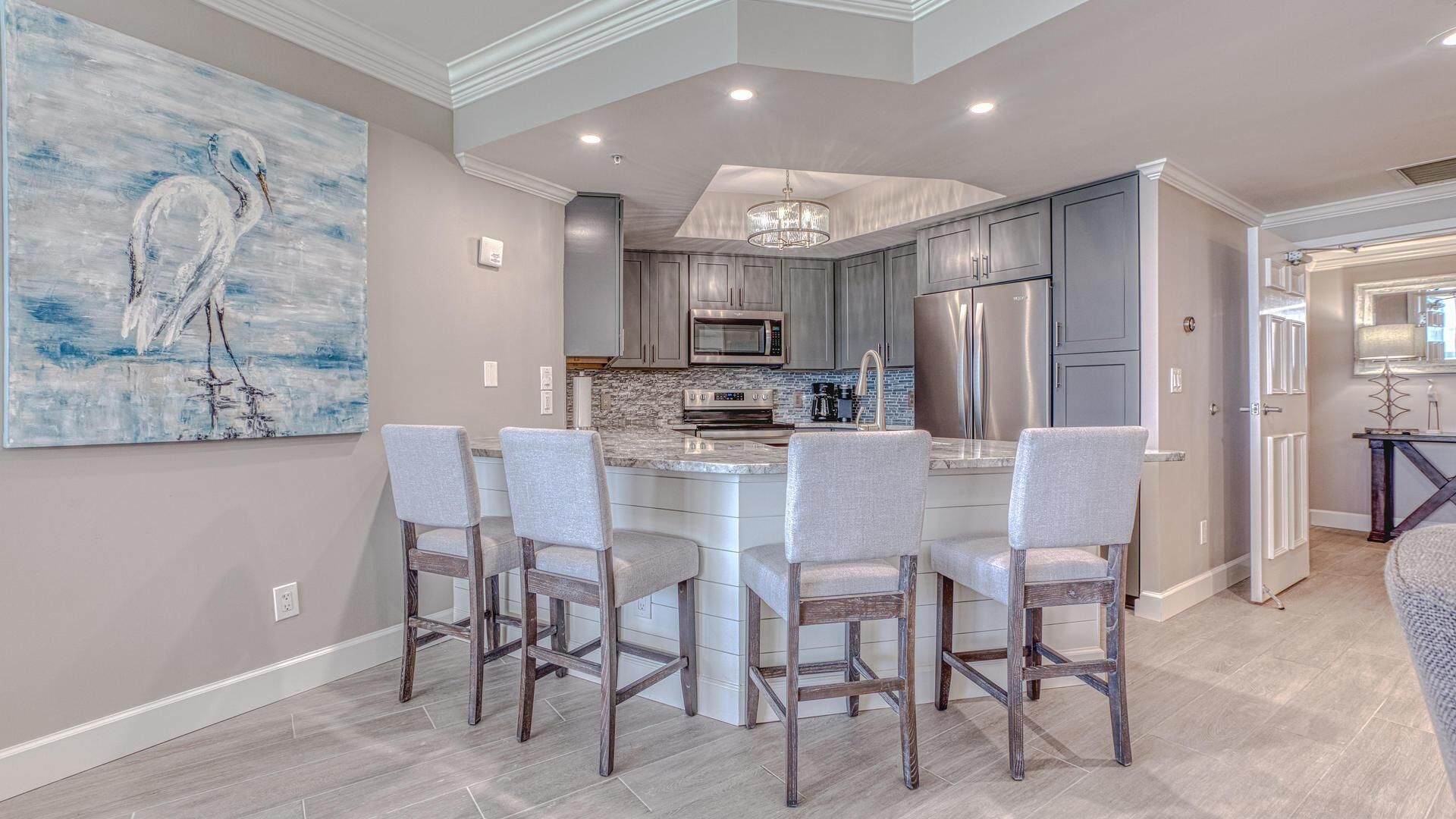 A modern kitchen with a central island, stainless steel appliances, and a chandelier.