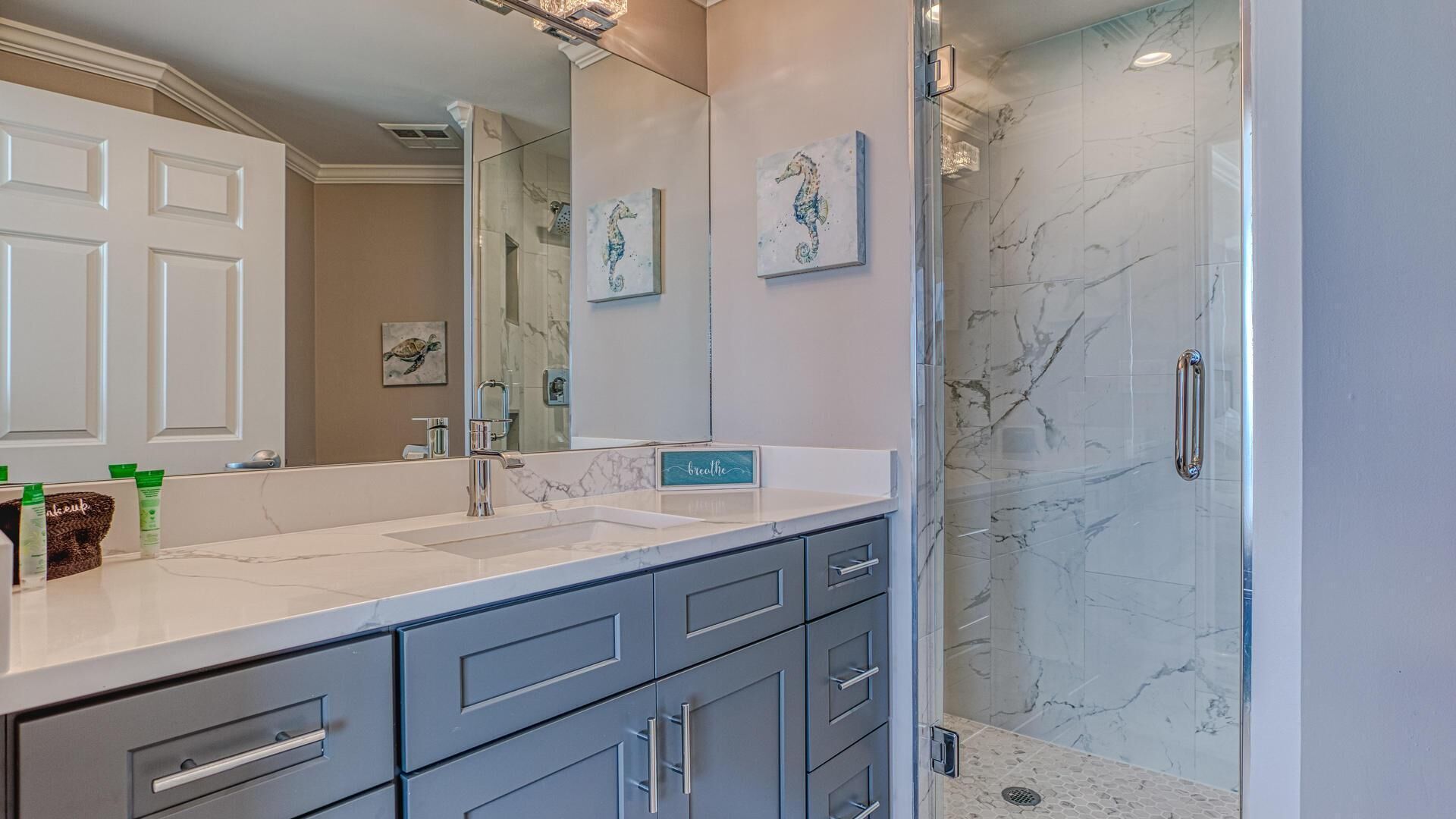 A bathroom with a large mirror, a sink, and a shower area.