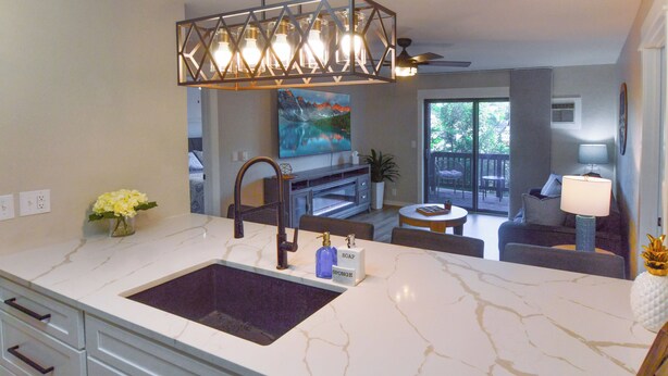A modern kitchen with a marble countertop, a built-in sink, and a pendant light fixture.