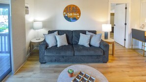 A living room with a grey sofa, two side tables with lamps, a small table with a plant and wooden blocks, and a wall sign that reads "LEAD South Dakota".