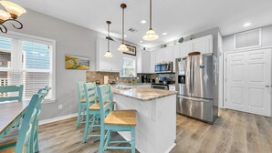 Una cocina moderna con armarios blancos, una isla central y electrodomésticos de acero inoxidable.