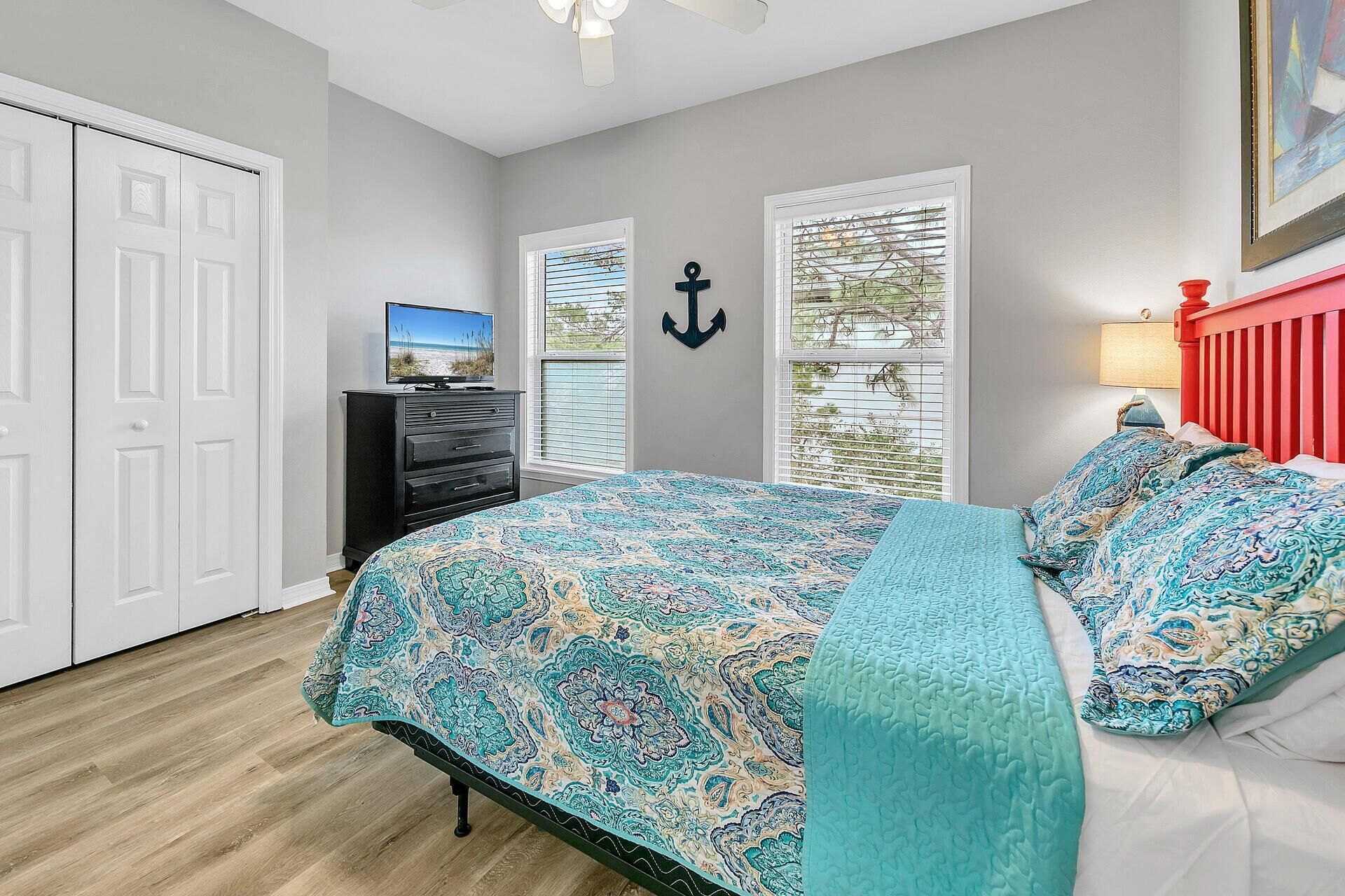 A bedroom with a bed, a dresser, a TV, and a window with blinds.