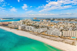 A coastal cityscape with beachfront hotels, a bridge, and a clear sky. - Aegean 204 (Destin)
