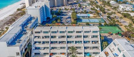 A hotel with multiple floors, a rooftop pool, and a beach view.