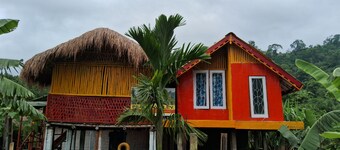“Elevated wood cabin and bamboo lounge combo in a lush mountain valley.” 