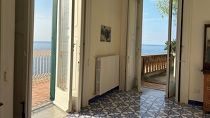 A hallway with a tiled floor leading to a balcony with a view of the sea.