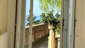 A doorway leading to a balcony with a view of the sea.