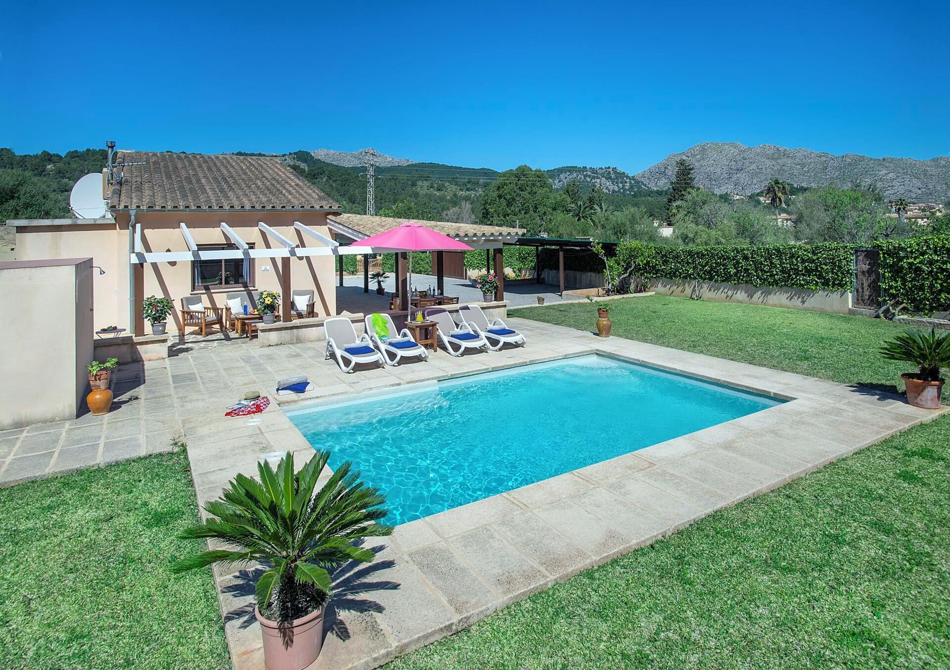 Une piscine avec des chaises longues, une pergola et une vue sur les montagnes.