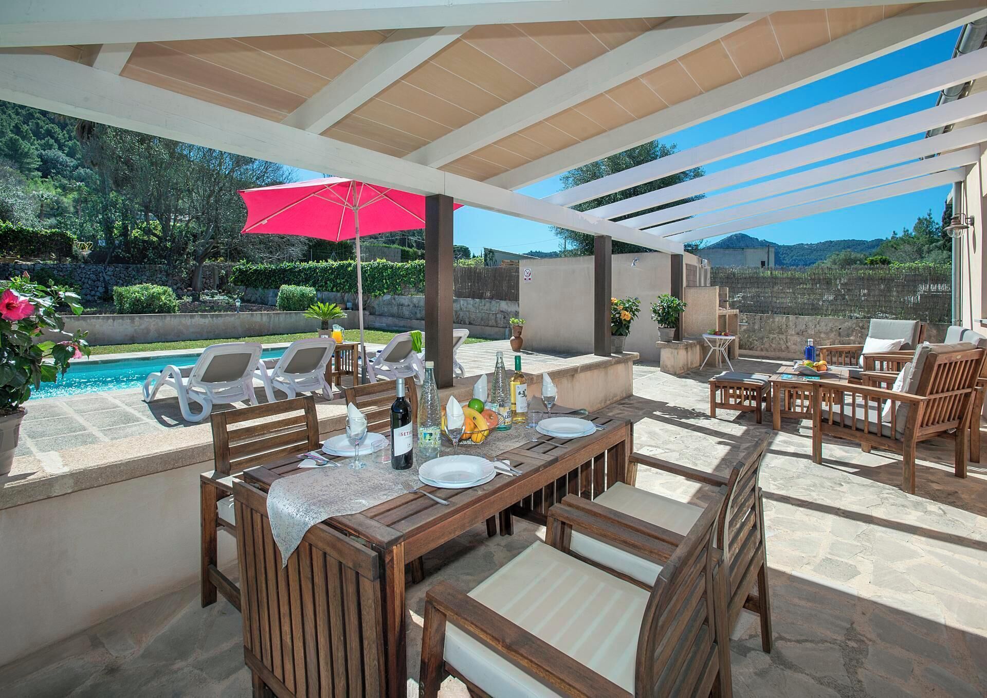 An outdoor patio with wooden furniture, a pool, and a view of the mountains.