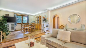 A spacious living room with a sofa, a dining area with a table and chairs, a television, and a cabinet. - Pretty Stone Finca, A/C, Private Pool, Large Grounds & Rural Views just 5mins from Old Town Pollenca (Pollença)