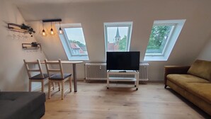 Un acogedor loft con comedor, televisor y sofá.