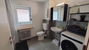 Et lille badeværelse med toilet, vask og vaskemaskine.