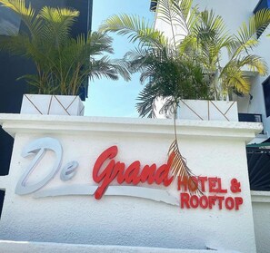A sign for De Grand Hotel & Rooftop with palm trees in the background. - De Grand Hotel and Rooftop (Calabar)