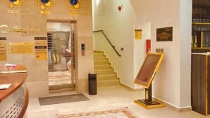 A hotel lobby with a reception desk, a staircase, and a signboard. - De Grand Hotel and Rooftop (Calabar)