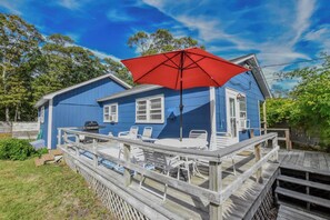 A blue house with a wooden deck, outdoor furniture, and a red umbrella. - Minutes to bayside beaches! (Eastham)