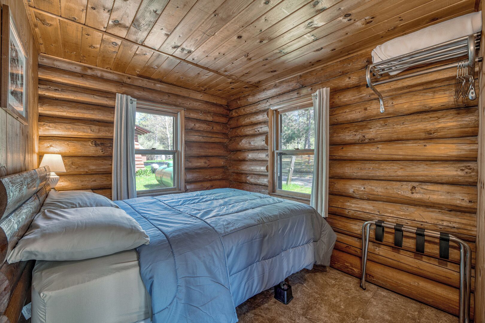 Un dormitorio tipo cabaña de madera con una cama, una mesita de noche, una ventana y un radiador.