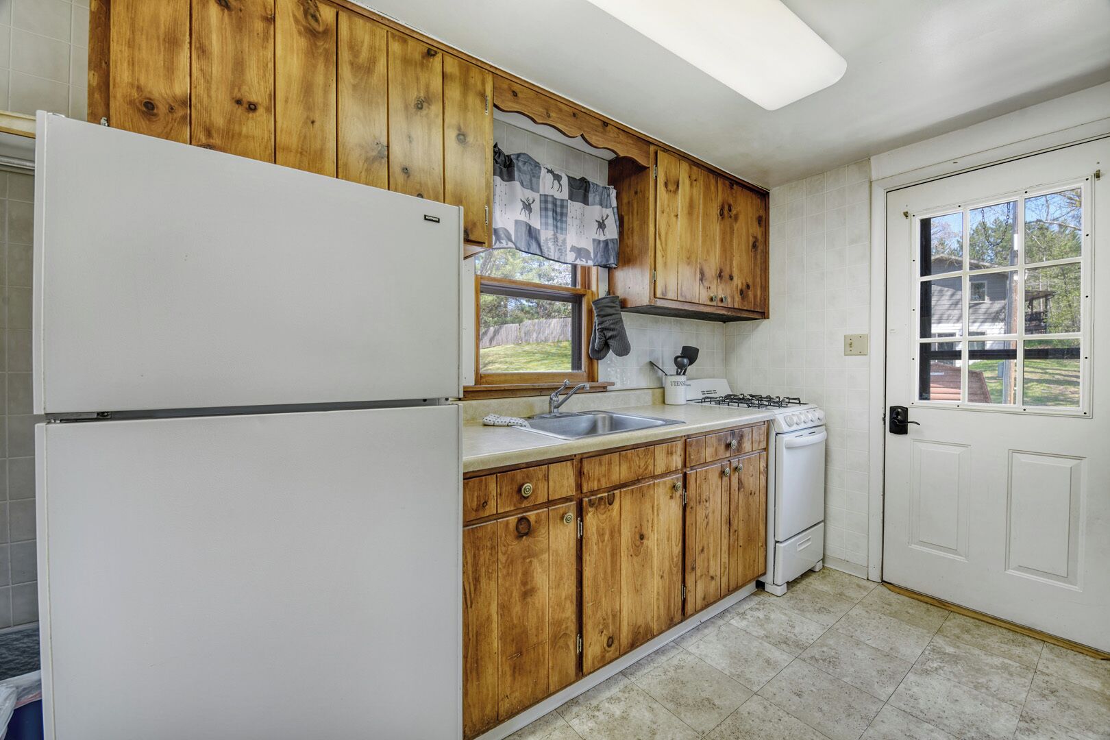 A kitchen with wooden cabinets, a white refrigerator, a sink, and a stove.