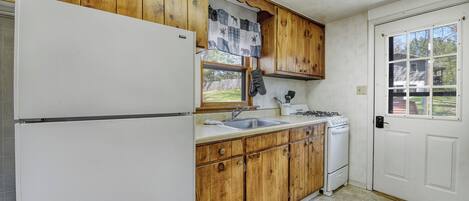 A kitchen with wooden cabinets, a white refrigerator, a sink, and a stove.