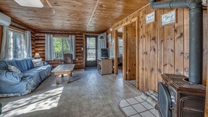 A log cabin interior with a sofa, TV, fireplace, and wooden walls. - Edgewater Resort (Iron Mountain)