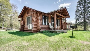 A log cabin with a porch, two chairs, and an air conditioning unit. - Edgewater Resort (Iron Mountain)