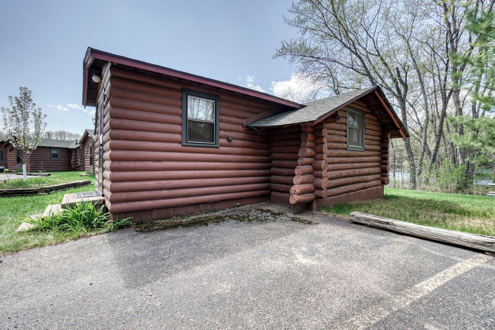 A log cabin with a porch and a small attached shed.