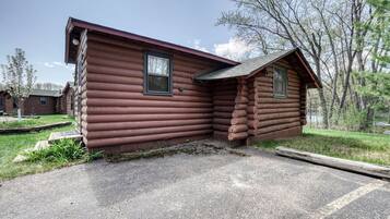 A log cabin with a porch and a small attached shed.