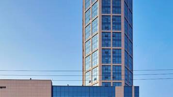 A tall, modern building with a glass facade and a beige exterior.