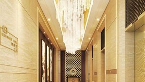Un pasillo de hotel con candelabro, paredes de mármol y diseño decorativo en las paredes.